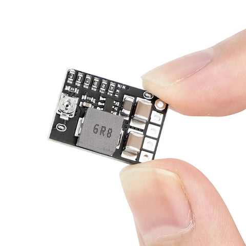 Close-up of a black mini DC buck converter board held by fingers, part of the Five Pack Mini DC Buck Converter Set 4.5 to 20V Input to 5V Output.