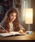 Girl studying by Touch Control Bedside Lamp With USB A And USB C Ports, 3-Way Dimmable Nightstand Light With White Fabric Shade