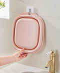 Collapsible Pink Wash Basin Set Of 2 Foldable Portable Laundry Basins hanging on wall in bathroom space saving design