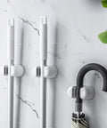 Three Pack Wall Mount Mop And Broom Holder Organizer with Self Adhesive Clips in bathroom holding mops and an umbrella on marble tile wall.