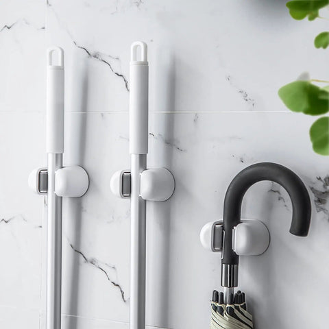 Three Pack Wall Mount Mop And Broom Holder Organizer with Self Adhesive Clips in bathroom holding mops and an umbrella on marble tile wall.