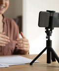 Smartphone mounted on black tripod with M6 Female To One Quarter Inch Male Tripod Screw Adapters Set Of Four In Durable Aluminum Alloy.