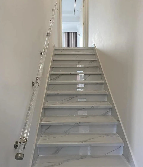 Crystal Clear Acrylic Stair Handrail With Chrome Brackets Delivers Hella Strong Safety Support For Indoor Homes Featuring Nonslip Transparent Pipe Handles In Multiple Custom Lengths Ideal For Elderly And Kids Wall Railing on a modern staircase.