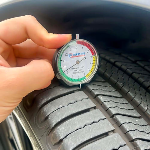 Pro Grade Dial Type Tire Tread Depth Gauge With 1/32 Inch Increments And 1/128 Inch Resolution placed on tire tread