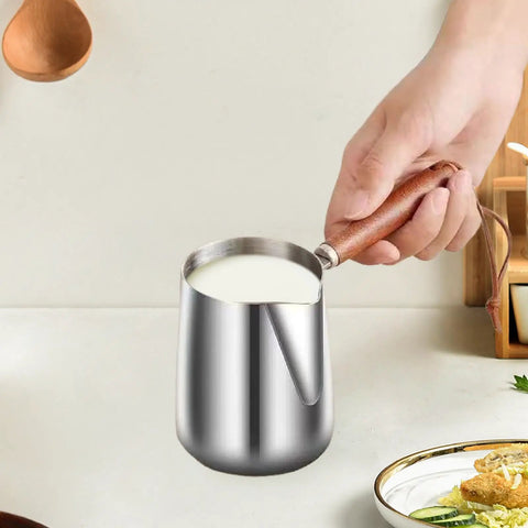 Hand holding Turkish Coffee Pot Stainless Steel Multipurpose Milk Frothing Pitcher And Coffee Kettle For Office Kitchen Home Bar 600ml Durable Spout With Wooden Handle Ideal For Latte Art