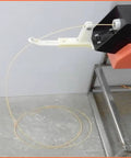 No Sweat 3D Filament Extruder Machine dispensing thin plastic filament loop on a workbench.