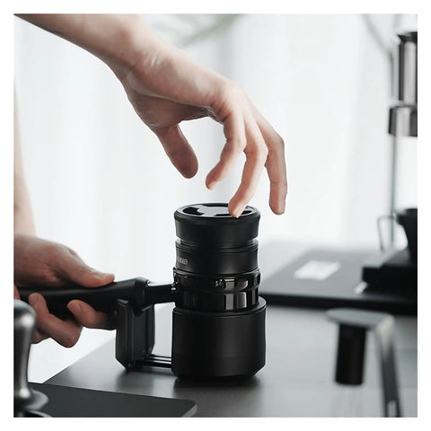 Hella Smooth Espresso Bed Leveler Cyclone Coffee Distributor Spinner in use with hand adjusting portafilter on black table.