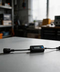 Hella Precise EV Charger Analyzer 8 To 120 Volts And 0 To 10 Amps on a table, showing LCD display for voltage and current monitoring.