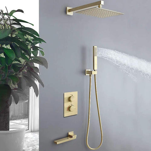 Brushed Gold Wall Mounted Shower System With Large Rainfall Head And Detachable Handheld Super Smooth Pressure Flow Instant Temperature Control Total Bathroom Glow Up Built Like A Tank For Everyday Luxury mounted on gray wall with water spray.