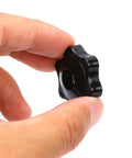 Close-up of black six-star knob with through-hole for 1/4-20 female thread, held by fingers.
