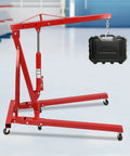 Heavy Duty 2 Ton Folding Engine Hoist With Rock Hard Carbon Steel Construction and Four Position Boom lifting a black case.