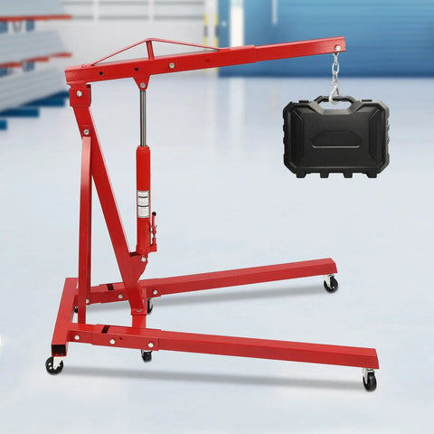 Heavy Duty 2 Ton Folding Engine Hoist With Rock Hard Carbon Steel Construction and Four Position Boom lifting a black case.