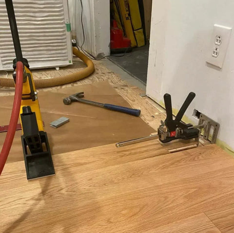 Viking Arm handheld jack/clamp with yellow base and black clamp, shown on wood floor near tools.