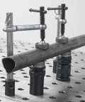 Inserta Clamps For 16mm Holes, Heavy Duty Workholding, 200mm Capacity, 100mm Throat, 181 kg Clamping Force, 20x10mm Rail, Vertical Or Horizontal Mount, Model UEN6200 holding a metal tube on a perforated table