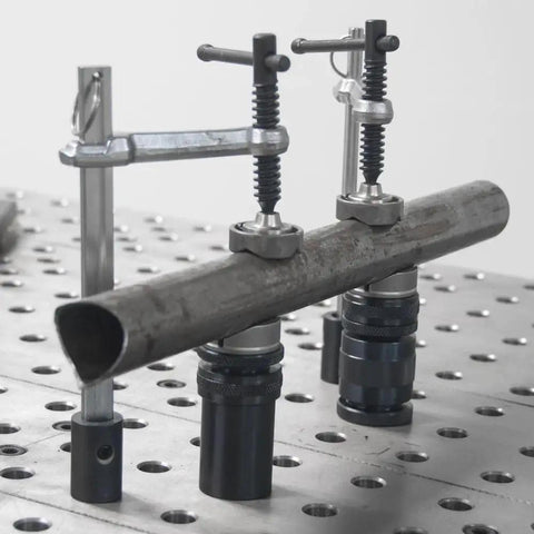 Inserta Clamps For 16mm Holes, Heavy Duty Workholding, 200mm Capacity, 100mm Throat, 181 kg Clamping Force, 20x10mm Rail, Vertical Or Horizontal Mount, Model UEN6200 holding a metal tube on a perforated table