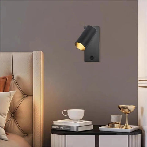 Modern Rotatable Cylinder Wall Sconce Wall Mount Reading Spotlight in black on a gray wall, illuminating a bedside area.