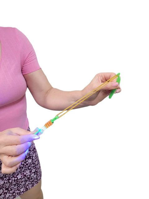Person holding a Cool LED Light Up Helicopters Slingshot Flying Toys Multicolor Pack Of 12 For Outdoor Play Bright LEDs That Fly Up To 100 Feet Easy To Use Totally Dope For Kids Party Favor For Backyard Fun, showing the slingshot mechanism.