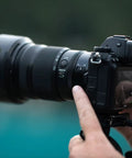 Person holding a camera with Nikkor Z 24-120mm F4 S Do It All Zoom Lens For Z Series Mirrorless Cameras, Constant Aperture From Wide To Telephoto, FX And DX Compatible, Close Focus To 1.15 Feet, Sharp, Versatile Travel Ready.