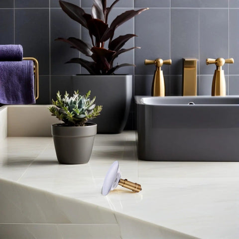 Copper Bathtub Drain Stopper with Bounce Design for Easy Control on marble countertop next to potted plants in modern bathroom setting.