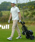Man pulling Electric Four Wheel Foldable Golf Cart Trolley With Easy Push Or Ride Options In Classic Black Trim across the green.