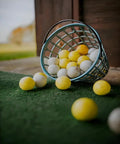 Golf Ball Basket With Handle Green Ball Bucket Holds Up To 25 Balls For Practice And Training on grass surface.