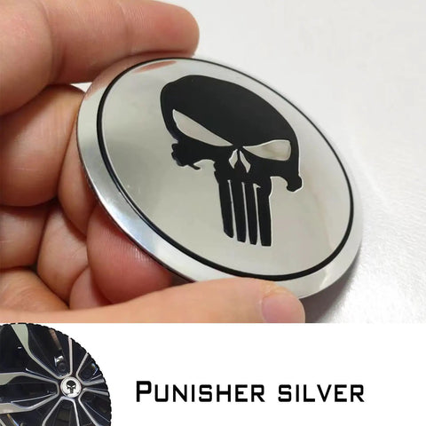 Four Piece Heavy Duty Aluminum Hub Center Cap Decals Featuring Dope Tusked Skull Art For Clean Wheel Cover Stickers That Slap Onto Most Standard Rims Smoothly, showing shiny silver skull cap decal held in hand.