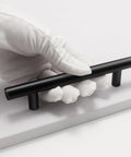 Gloved hand holding matte black handle from 15 Pack Black Cabinet Handles 5 Inch Stainless Steel Drawer Pulls With Precise Hole Spacing