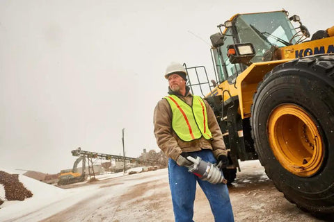 Heavy Duty 1 1/2 Inch Air Impact Wrench With D Handle held by worker near a Komatsu loader during snow.