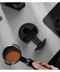 Adjustable Espresso Tamping Station For Home Cafe Setups Fits 51mm 53mm And 58mm Portafilters on a countertop with portafilter.