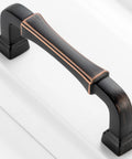Close-up of a 10 Pack 3 Inch Oil Rubbed Bronze Cabinet Pull with Bronze Brushed Finish on a white cabinet, featuring smooth edges.