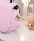 Close-up of Top Shelf Gold Brass D Rings For Purse 4 Pack With Screw Back Rotatable Strap Hardware on a pink handbag.