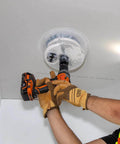 Klein Tools 53710 hole saw attached to orange cordless drill cutting drywall ceiling tile with integrated dust bowl