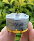 Close-up of RC500-KN Mini 32mm Round Spindle Motor held in hand, showcasing DC 6V 12V, 5300 RPM for robots, vacuums, and DIY projects.
