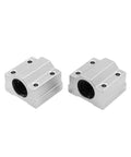Two aluminum linear bearing slide blocks with mounting holes and circular bore, front view