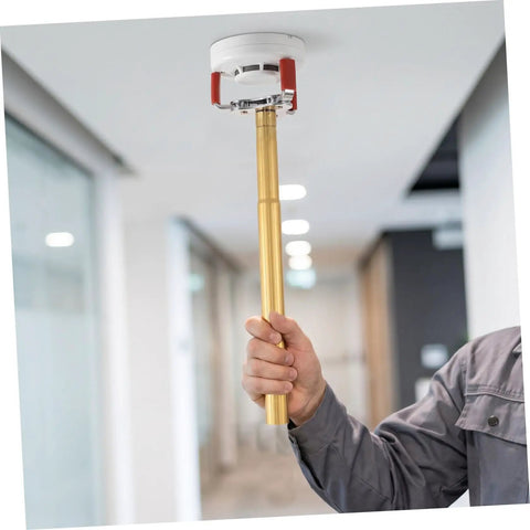 No Sweat Premium Smoke Sensor Removal Tool With Heavy Duty Claw Head Aluminum Body Ladder Free Ceiling Detector Puller in use to retrieve smoke alarm.
