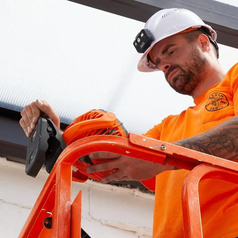 Worker installing Cordless Rechargeable Fan With USB-C Charging Cord And Multiple Mounting Options For The Jobsite on a ladder