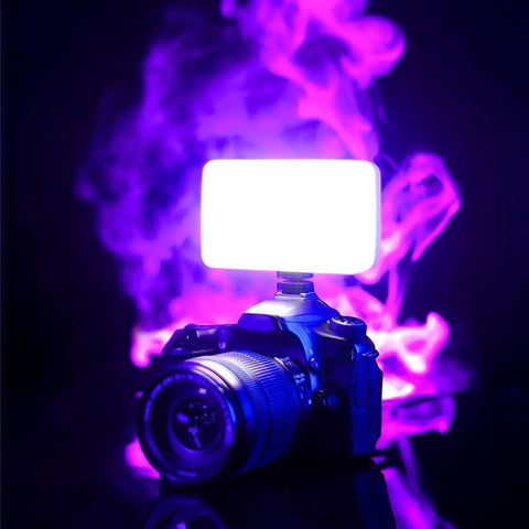 On-Camera Bi-Color LED Video Light With 6 Color Filters on DSLR camera, glowing brightly against a purple smoke backdrop.