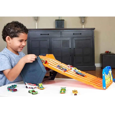 Child playing with Roll Out Raceway Track Set With Cool Collapsible Design And Built In Storage For Up To Eighty Die Cast Cars And Five Track Pieces Portable Carry Handle Easy Grab And Go Racing Fun For Kids, showing orange five-lane track and die-cast cars.