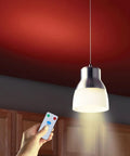 Person holding remote near hanging light, using Go To Rechargeable LED Light Bulbs With Remote Control Cordless Warm White Emergency Lamp.