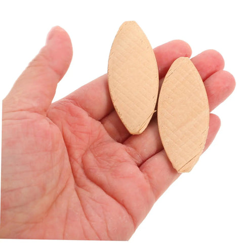 Close-up of two light yellow hardwood biscuits held in hand for 100 Piece Hardwood Biscuit Joiner Set for Woodworkers.