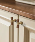 Close-up of Six Pack Antique Brass Walnut Cabinet Pulls And Knobs Set on cream kitchen cabinets, 3.78 Inch Hole Center