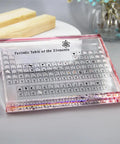 Cool Pink Acrylic Periodic Table Display With Real Elements Inside On Wooden Stand 83 Samples Gift Box Packaging Ideal For Science Teachers And Students Classroom Decor Or Home Lab Showpiece, shown on a desk with soft lighting.