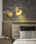Badass Industrial Metal Swing Arm Wall Sconce With Rock Solid Adjustable Dome Shade And E27 Socket Hella Sturdy For Bedroom Reading Vibes And Slick Black Brass Finish Modern Wall Lamp angled view with gold finish in bedroom setting.