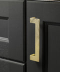 Five Pack Gold Cabinet Pulls 5 Inch Center To Center Brushed Brass Drawer Handles for bathroom cabinets, black door view.