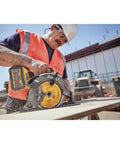 Worker using Flexvolt 60V Max Cordless Circular Saw With Brake 7-1/4 Inch, cutting wood on a construction site.