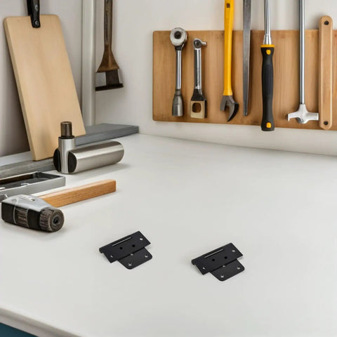 Two black Beefy Heavy Duty Shed Hinges For Barn Doors And Fence Gates on a workbench with tools in the background.
