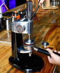 Gotta Have This Straight Fire Pro Grade Stainless Steel Coffee Tamper With Accurate Dial Gauge in use at a cafe.