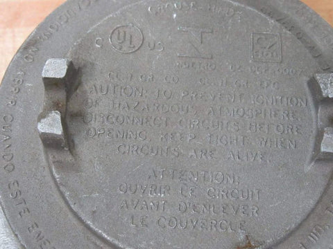 Front view of round metal Crouse-Hinds explosion-proof junction box cover, 2 in, with embossed warning text and side lugs.