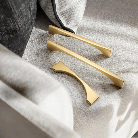 Three brushed gold cabinet drawer pulls on fabric surface, part of 4 Pack Brushed Gold Cabinet Drawer Pulls In Zinc Alloy With Brushed Brass Finish.