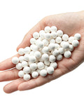 Hand holding 8 Pound Ceramic Tumbling Media Balls For Rock Tumblers Reusable White Alumina Pellets Three Tenths Inch Diameter Grit